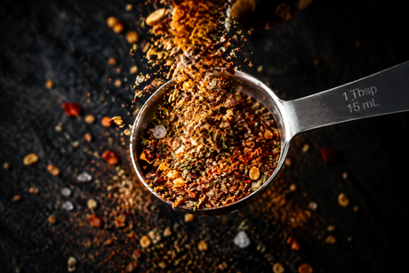 One tablespoon measuring spoon filled with seasoning blend