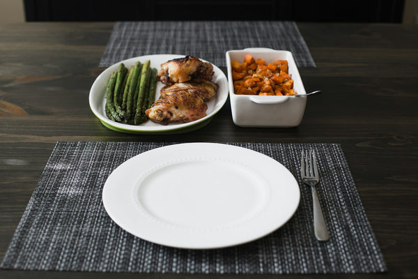 Grilled chicken thighs on a plate with roasted sweet potato and asparagus