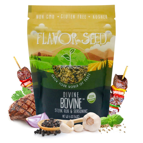 A Flavor Seed Divine Bovine organic steak rub pouch on a white background, with a grilled steak, two beef and pepper kebabs, half a red onion, a wooden spoon of black peppercorns, garlic and fresh herbs around it.