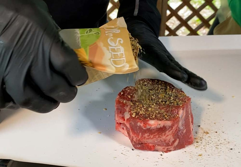 Seasoning steak ribeye with montreal steak spices for grilling