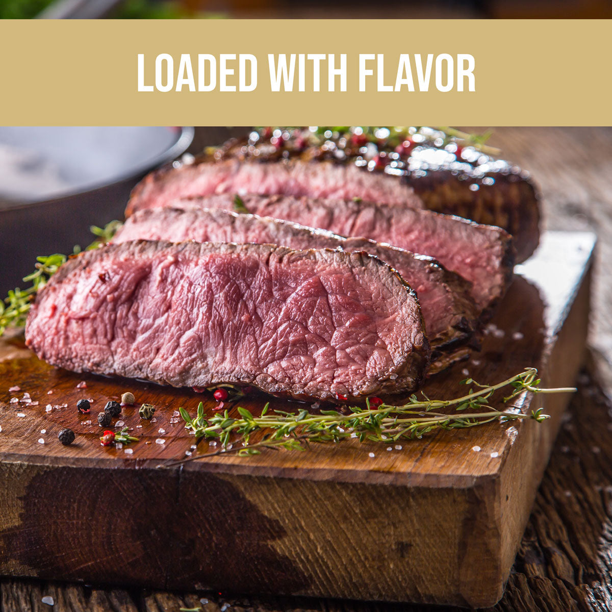 medium steak cut up on wooden board with fresh herbs and organic steak seasoning